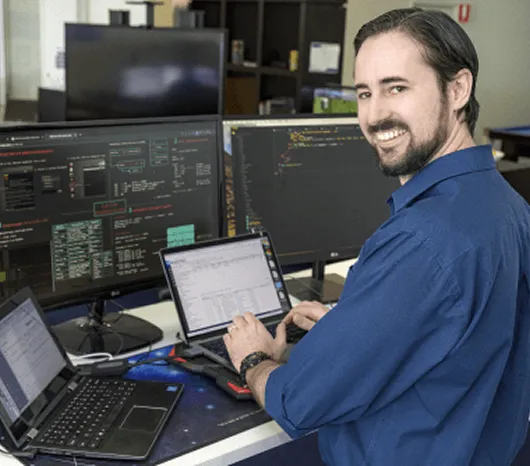 A DakTech technician at a desk with three monitors