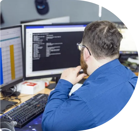 A developer in a blue shirt working at a monitor