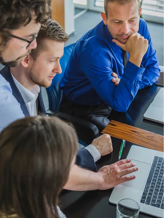 Three colleagues reviewing work on a laptop