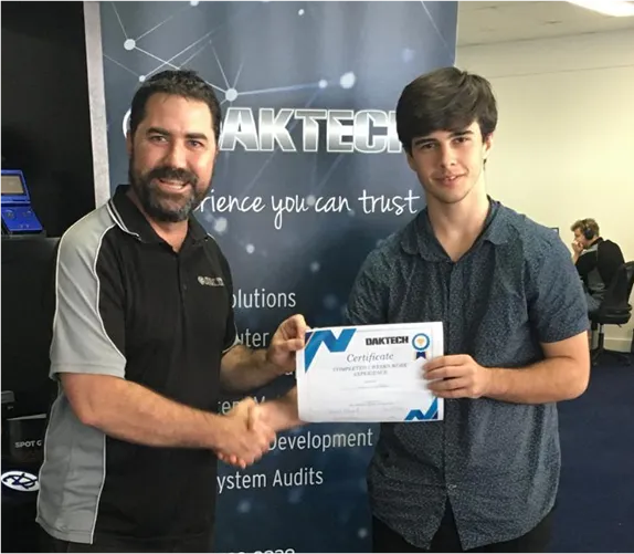 Daniel Kendall presenting a certificate to a student at the DakTech stand