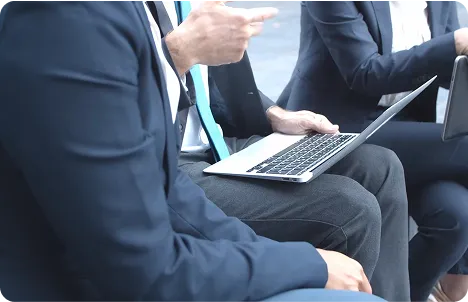 Two people in business wear working together on a laptop